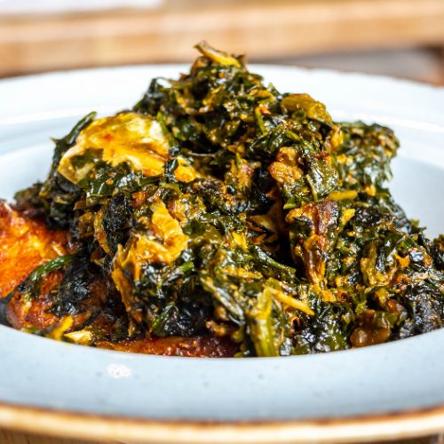 A white plate of Nigerian vegetable Efo Riro soup soup on a white background