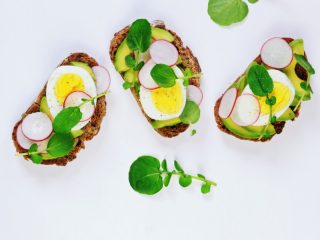 Three pieces of an egg avocado sandiwich lying next to each other on a white background