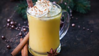 Eggnog topped with whipped cream and stick of cinnamon