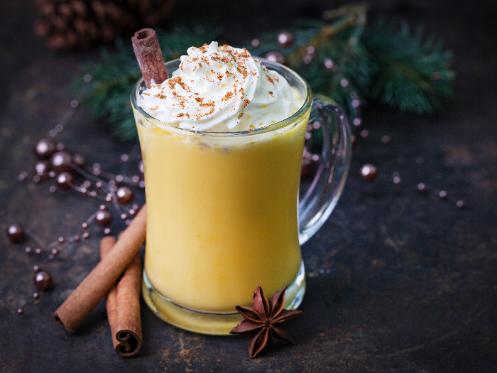 Eggnog topped with whipped cream and stick of cinnamon