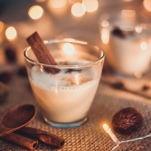 Eggnog in glasses with star anise and cinnamon on wooden table for Christmas and winter holidays