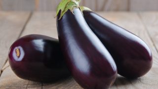 A close-up view of fresh eggplants placed on a wooden table