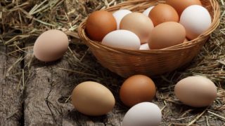 Brown and white eggs in a cane basket on a wooden counter