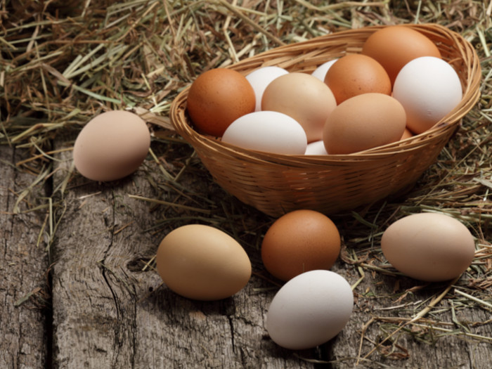 Brown and white eggs in a cane basket on a wooden counter
