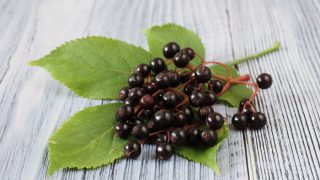 Fresh elderberries on a leaf on a wooden table
