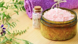 A bowl and a bottle of epsom salt with towels and leaves