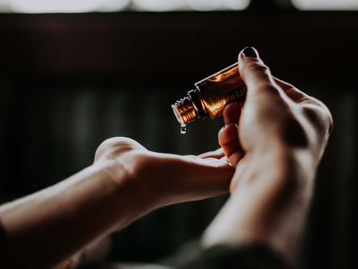 A woman pouring essential oil drop by drop in her hand