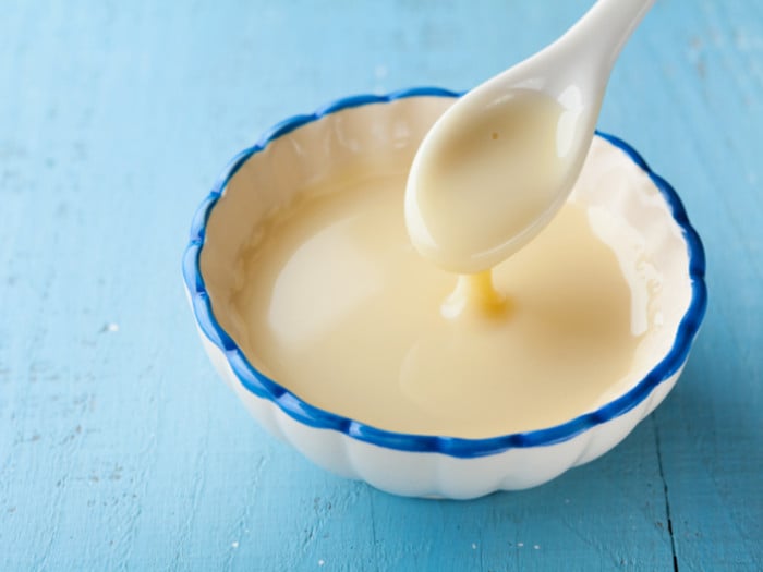 A bowl of evaporated milk on a light blue surface