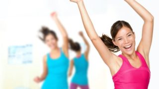 Women in gym clothes, exercising and smiling