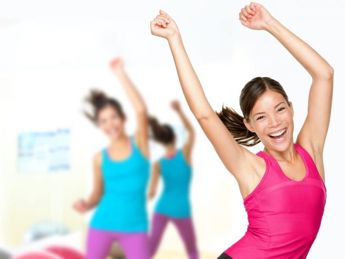 Women in gym clothes, exercising and smiling