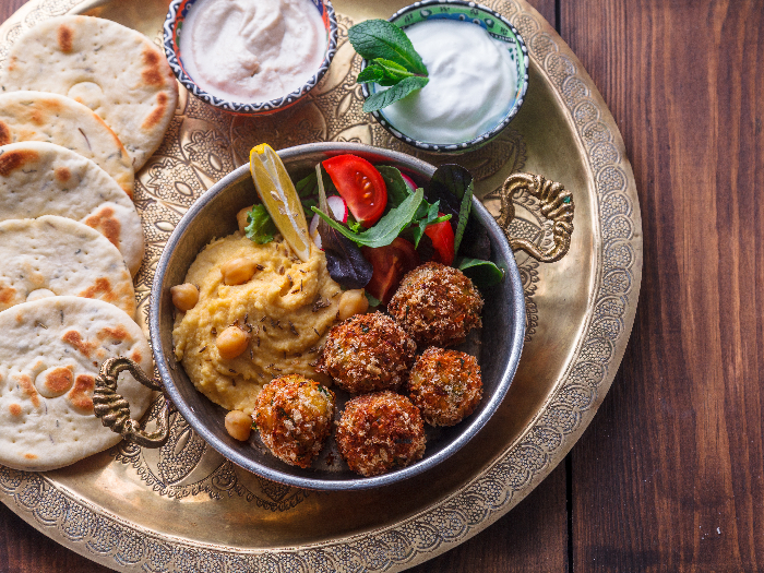 Hummus, falafel, salad in a pan with yoghurt and tahini