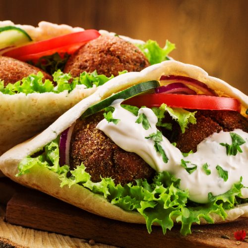 Falafel and fresh vegetables in pita bread on wooden table