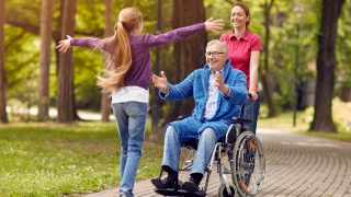Grandfather in wheelchair welcoming his happy granddaughter
