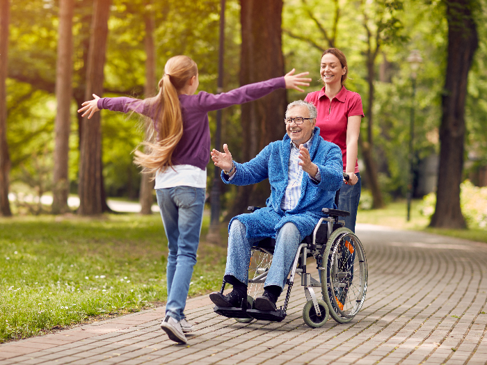Grandfather in wheelchair welcoming his happy granddaughter