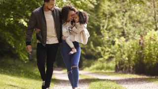 Family of three on a walk, mother holding the child 