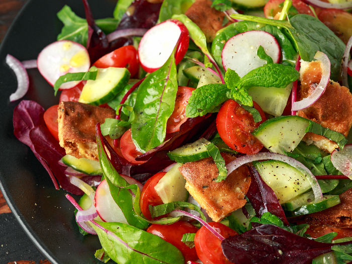 Traditional fattoush salad on a plate with pita croutons, cucumber, tomato, red onion, vegetables mix and herbs