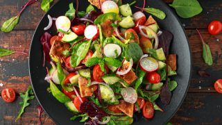 Traditional fattoush salad on a plate with pita croutons, cucumber, tomato, red onion, vegetables mix and herbs