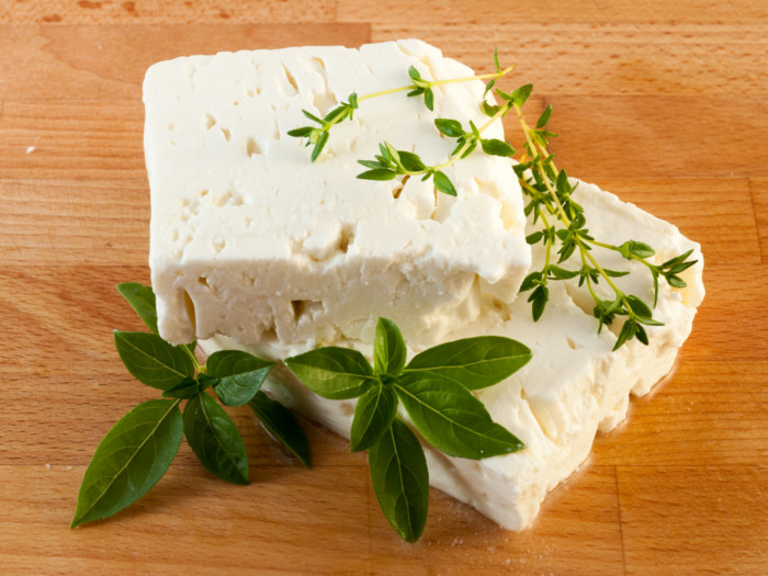 Two blocks of cheese and sprigs of oregano and mint.