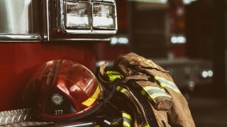 firefighter jacket and helmet laid on the front of a firefighters truck