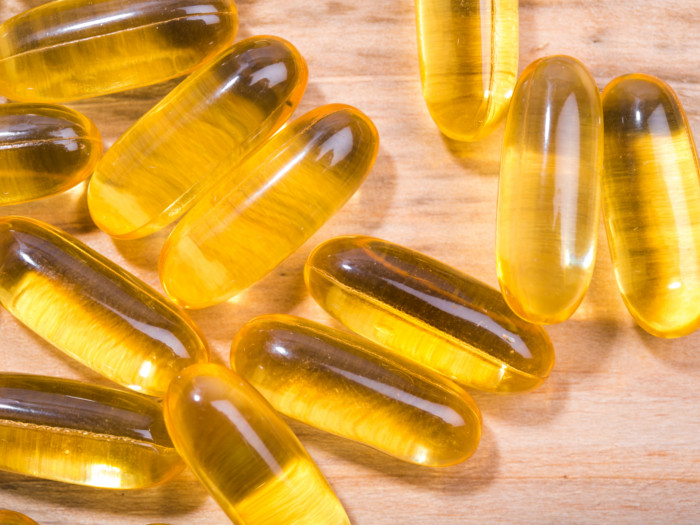 Close up of yellow capsules on a wooden counter