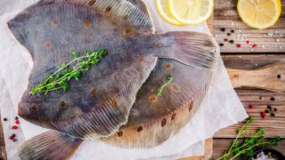 Two flounder fish garnished with herbs on a table