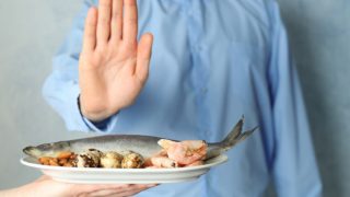 A young man refusing to eat foods - fish, prawns, and almonds that may cause food allergy