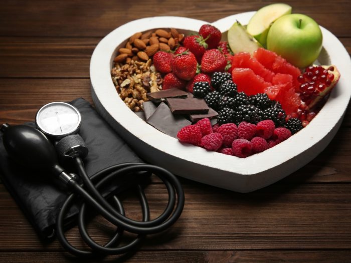 A heart-shaped plate filled with heart-friendly foods such as dark chocolate, berries, fruits, and nuts