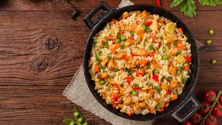A flat lay pic of fried rice kept in a black wok placed on a wooden table