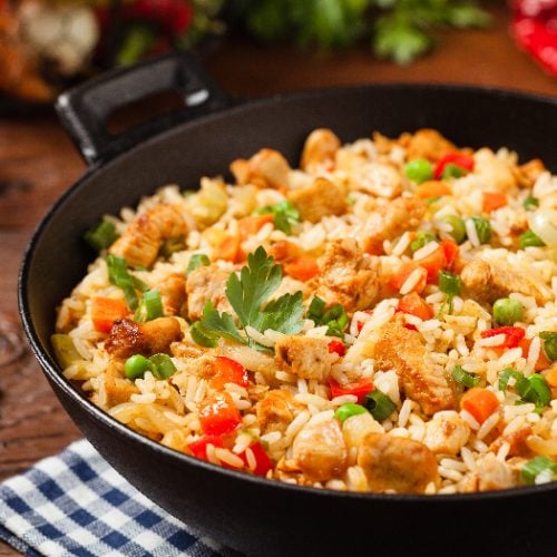 A close up shot of fried rice prepared and served in a wok against a wooden background