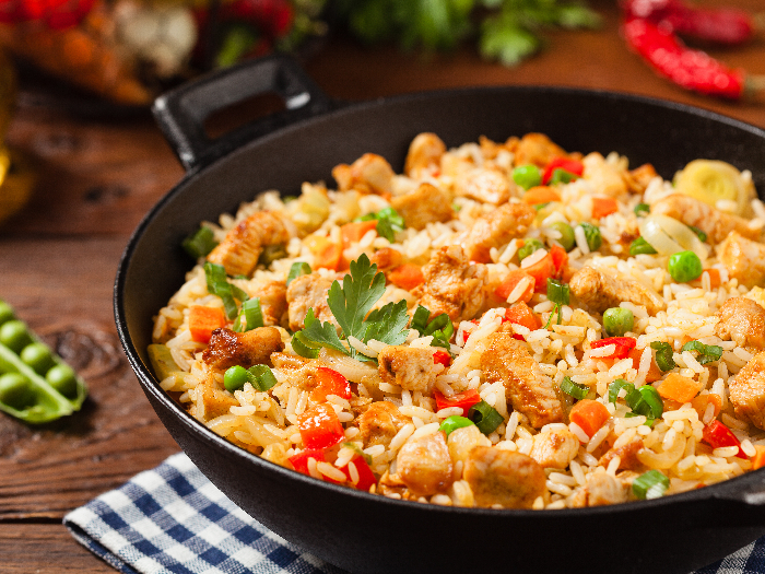 A close up shot of fried rice prepared and served in a wok against a wooden background