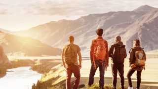 Four friends looking at a sunset, mountains, and river