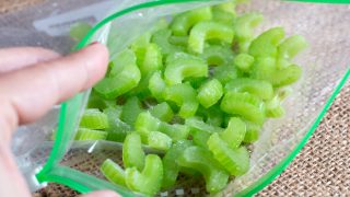 Frozen pieces of celery in a bag on a wooden board