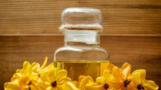 A bottle with essential oil with yellow blossoms kept next to it