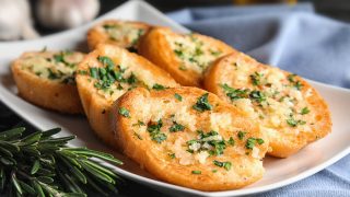 Plate with delicious homemade garlic bread on table