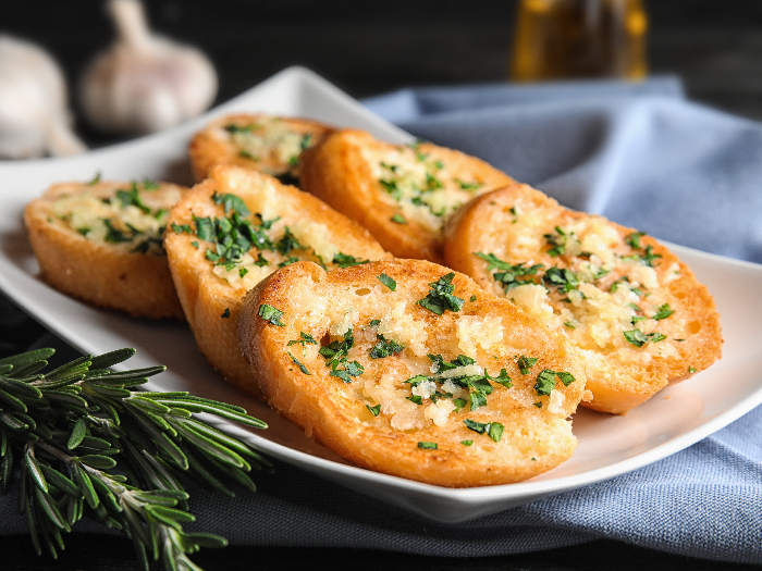 Plate with delicious homemade garlic bread on table