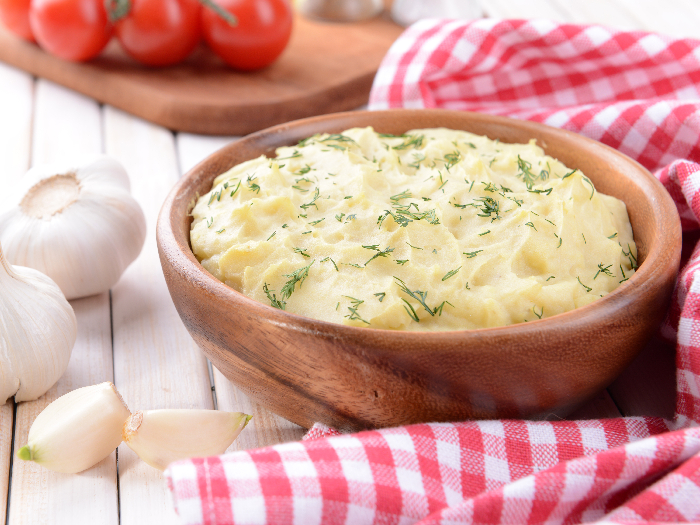 A closeup picture of delicious mashed potatoes with greens in bowl on table close