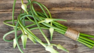 A bunch of garlic scapes tied with twine on a wooden counter