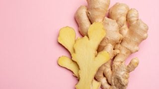 Close-up of peeled and whole ginger on a pink background