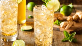 Tall glasses of ginger beer with lime, mint, and ice cubes