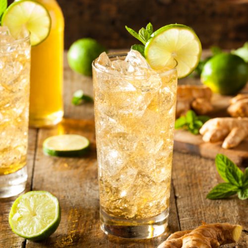 Tall glasses of ginger beer with lime, mint, and ice cubes