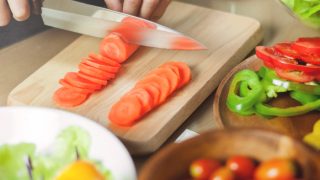A woman cutting carrots for the glazed carrot recipe