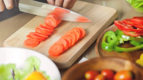 A woman cutting carrots for the glazed carrot recipe