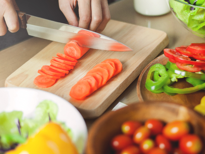 A woman cutting carrots for the glazed carrot recipe