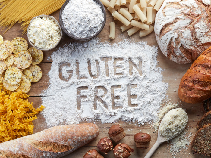 Flatlay view of a board saying gluten free, surrounded by cookies, flours, pasta, bread, and muffins.