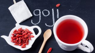 Goji berries on a kettle-shaped plate, a spoon, and a cup of tea