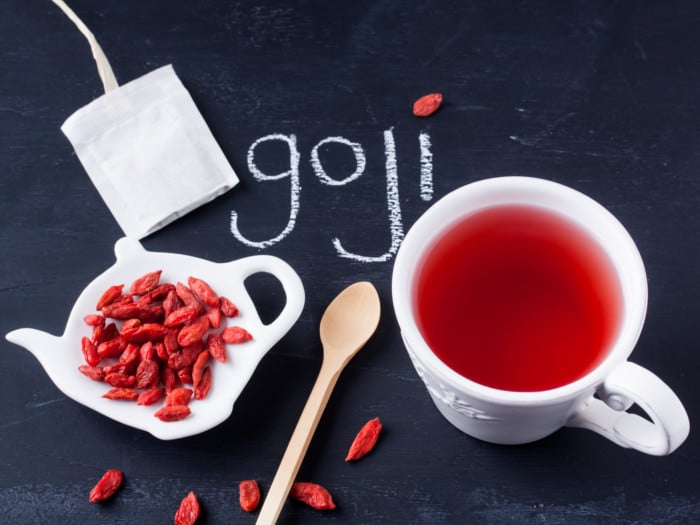 Goji berries on a kettle-shaped plate, a spoon, and a cup of tea