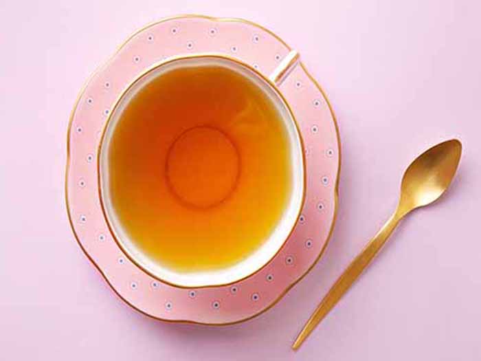 Flatline view of tea in an elegant cup and saucer with a spoon placed alongside