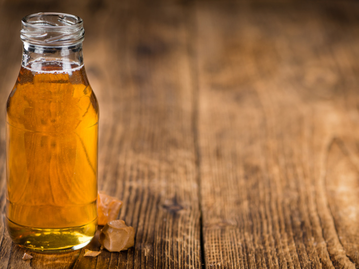 Golden syrup in a glass bottle kept atop a wooden table