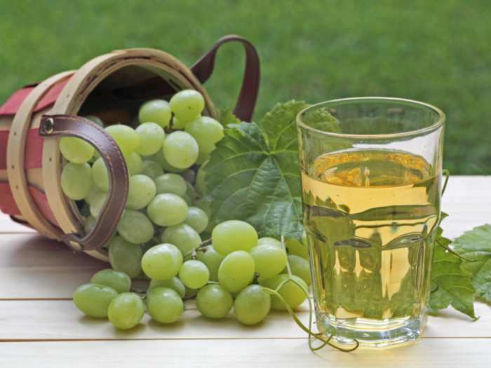 A bunch of grapes and grape juice kept on a white table in the garden