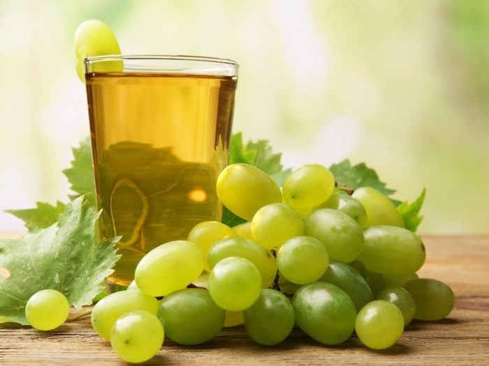 A glass of grape juice kept next to green grapes